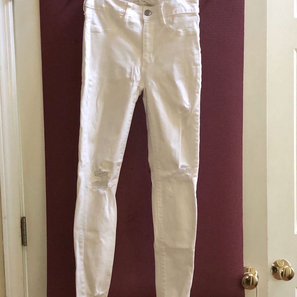 White distressed denim jeans with silver buttons.